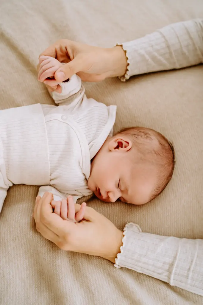 Mama hält die Hände von ihrem Baby fest