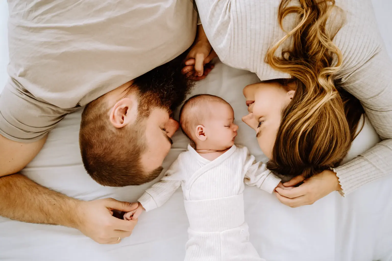 Mama, Papa und Baby liegen auf einer Decke für ein wunderschönes Babyfoto
