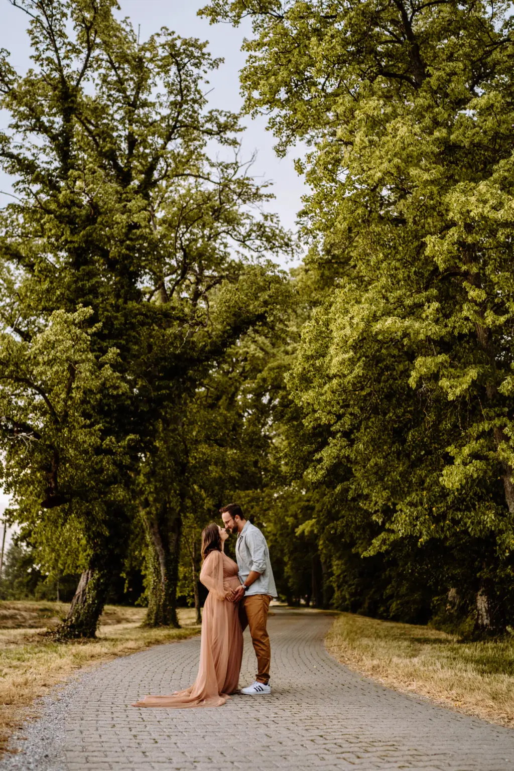 Paar in enger Umarmung auf einem Weg in der Natur am Starnberger See, Babybauch sichtbar, natürliche Farben