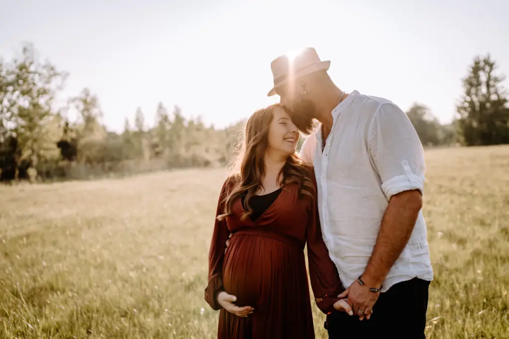 Silhouette auf der Wiese bei tief stehender Sonne, Babybauch als Mittelpunkt - Babybauchfotos in der Natur