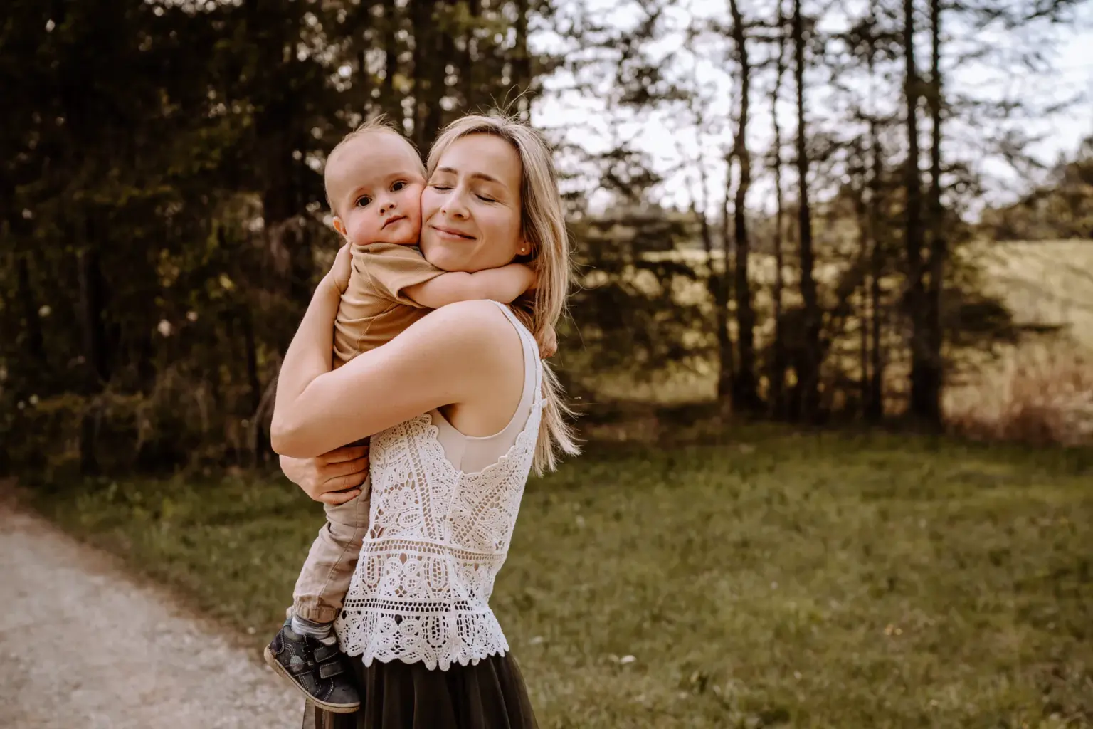 Mama knuddelt Kind am Waldrand, ungestellte Familienfotos mit Gefühl