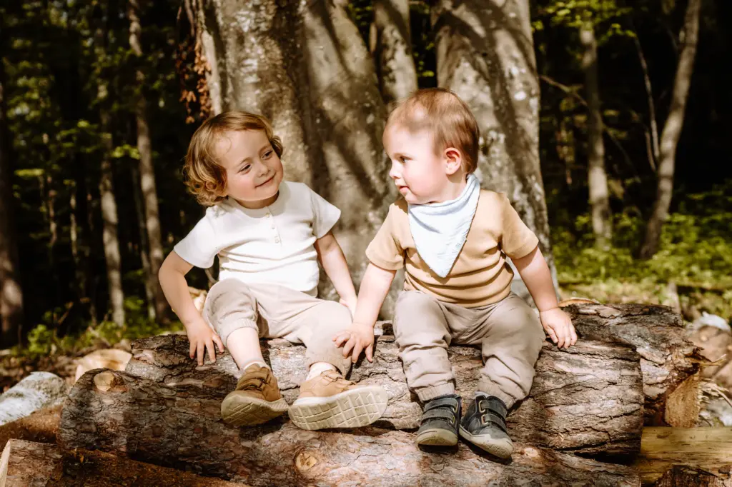 Kinder sitzen fröhlich auf einem Baumstamm