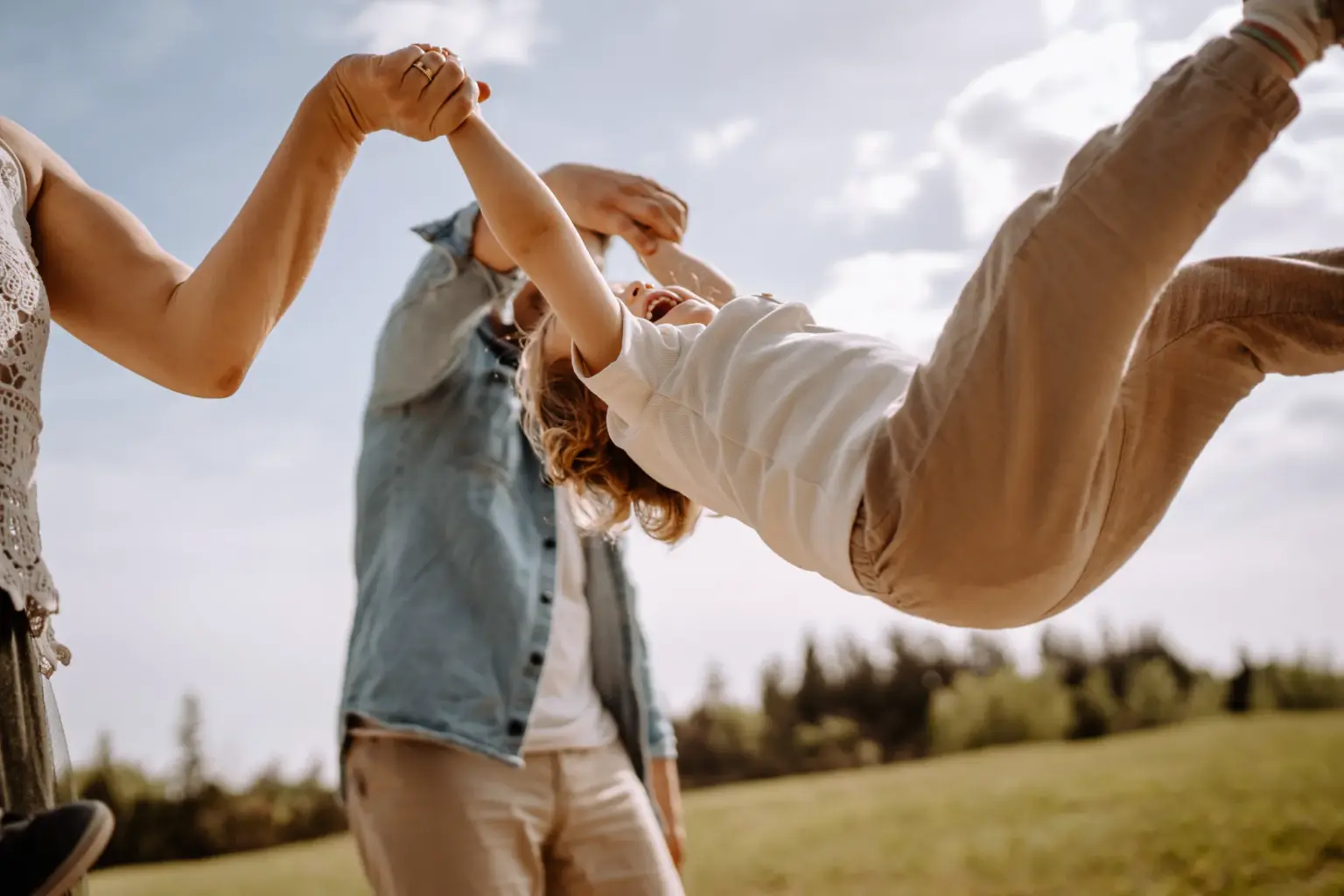 Engelchen flieg mit dem Kind - Mama und Papa halten ihr Kind in der Mitte