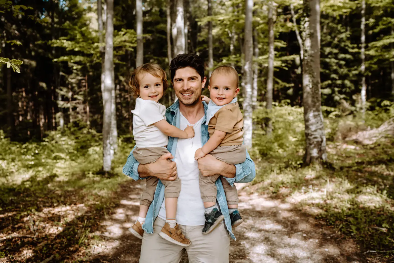 Papa hebt Kinder hoch auf der Wiese, Familienfoto mit Spaß und Action