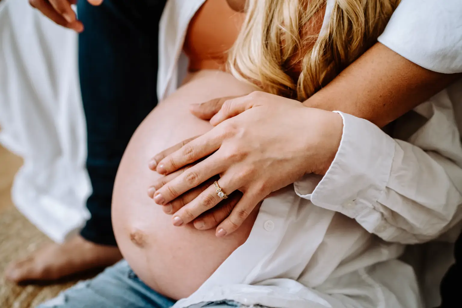Hand auf Babybauch, andere Hand hält Partnerhand, Studio Weilheim