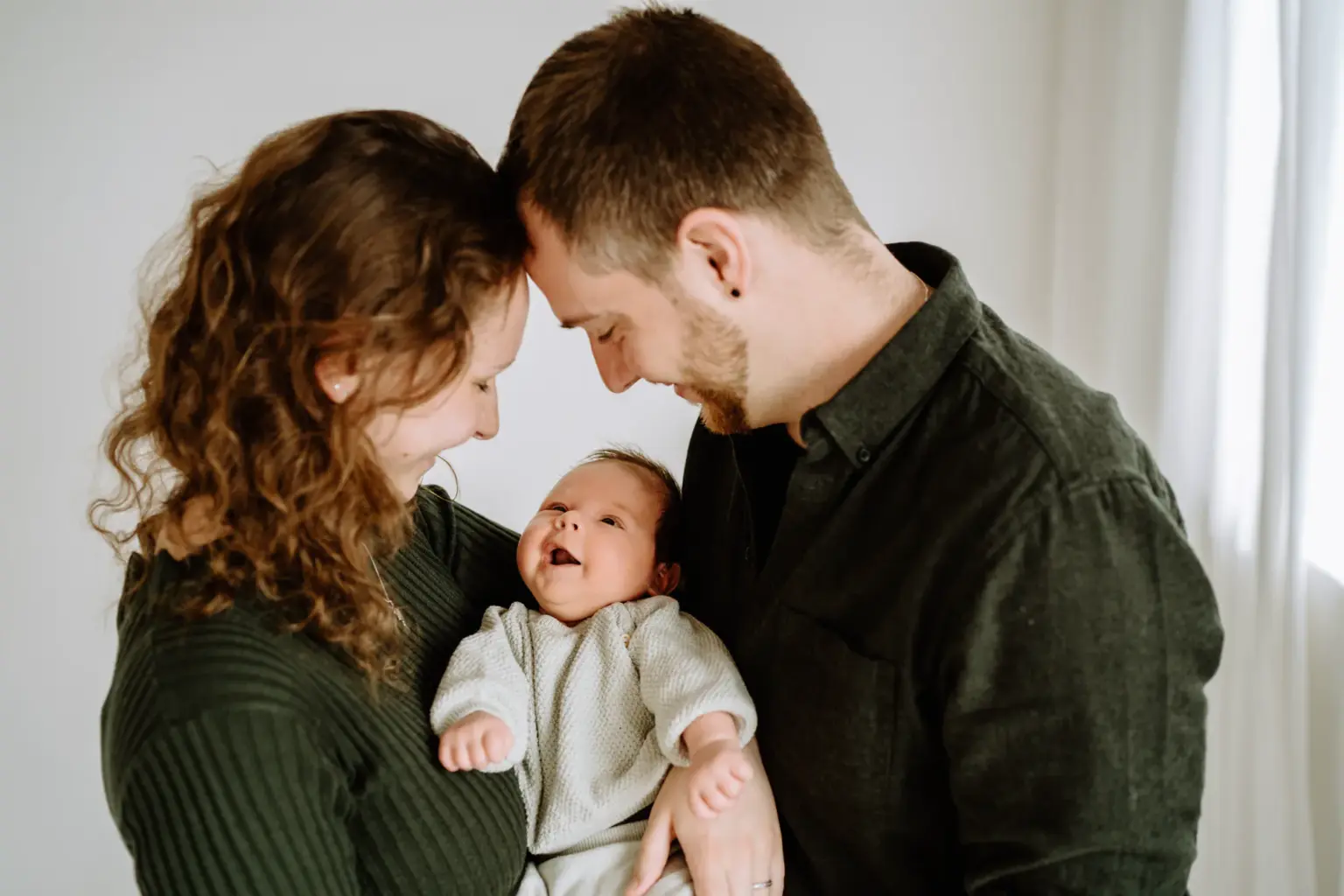Eltern halten Baby im Arm, Familienfoto im Fotostudio Weilheim, viel Weiß