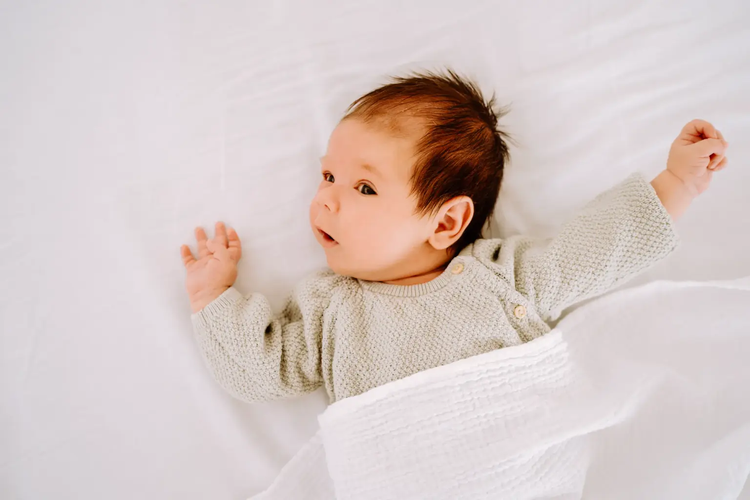 Baby liegt eingekuschelt in weißer Decke, Studio Weilheim, natürlicher Stil
