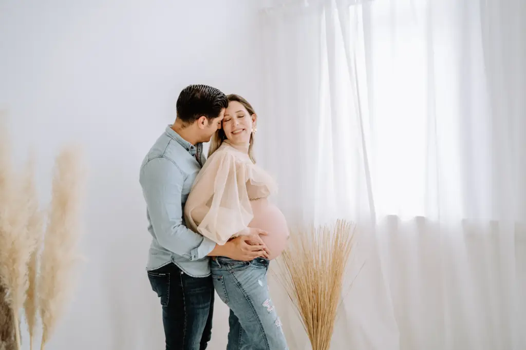 Paarfoto mit Babybauch im Fotostudio Weilheim, natürliche Nähe, cleanes Weiß