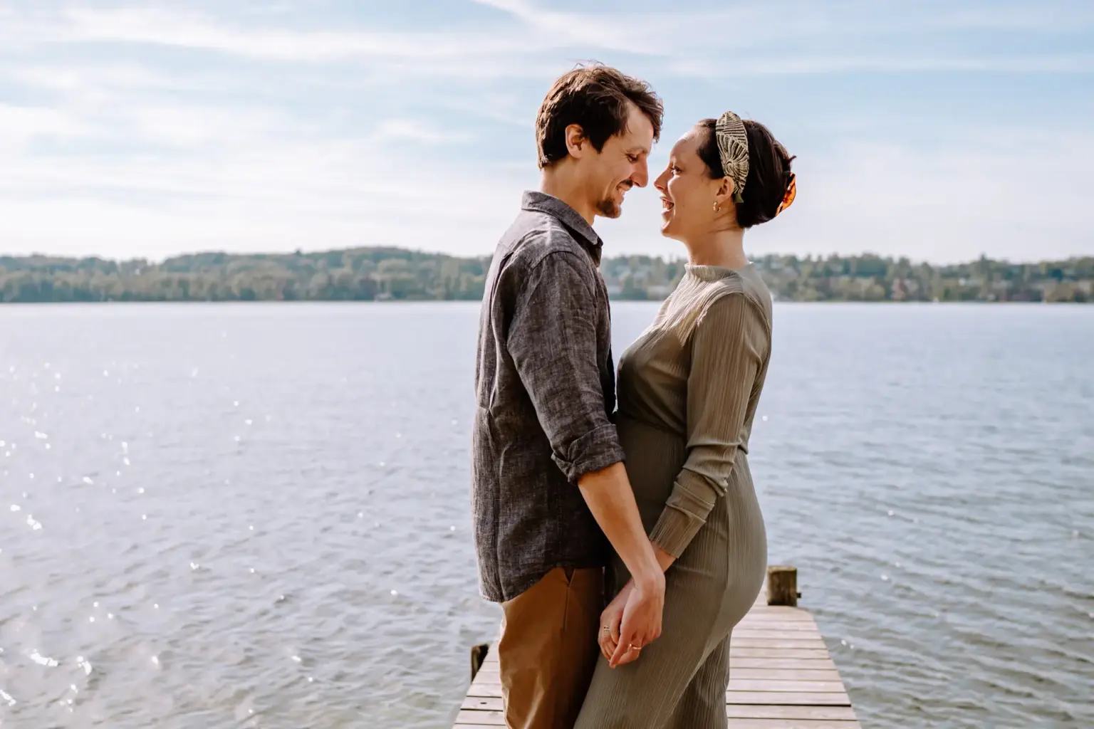 Paar küsst sich auf dem Steg, Babybauch Shooting, echte Verbindung