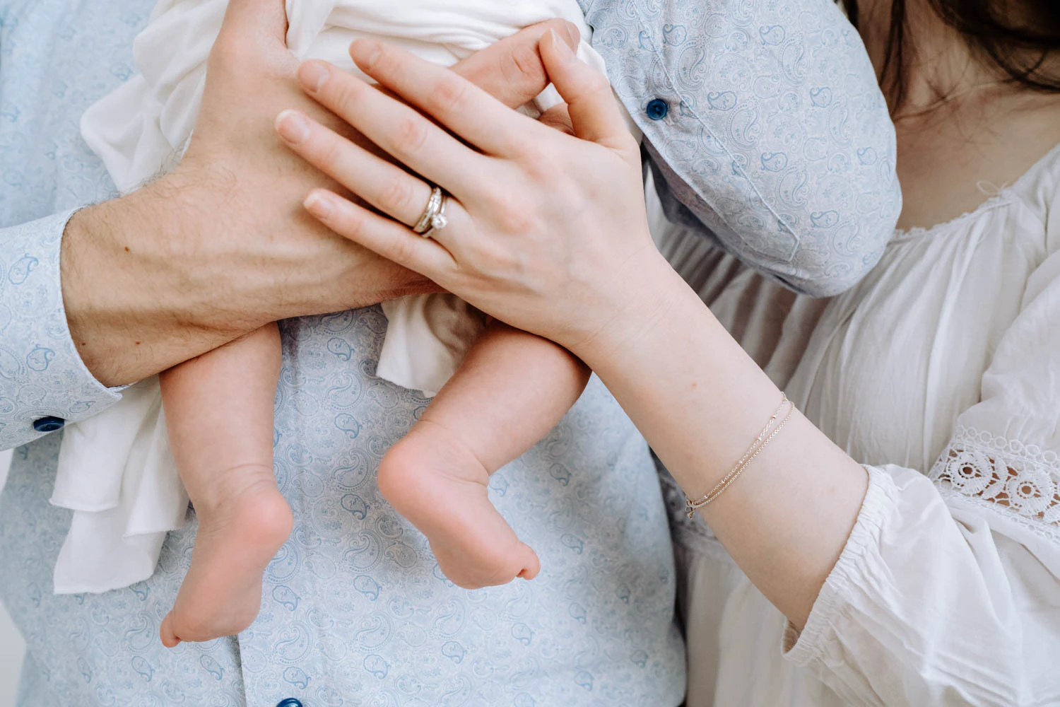 Hände der Eltern umschließen Baby, minimalistische Bildsprache