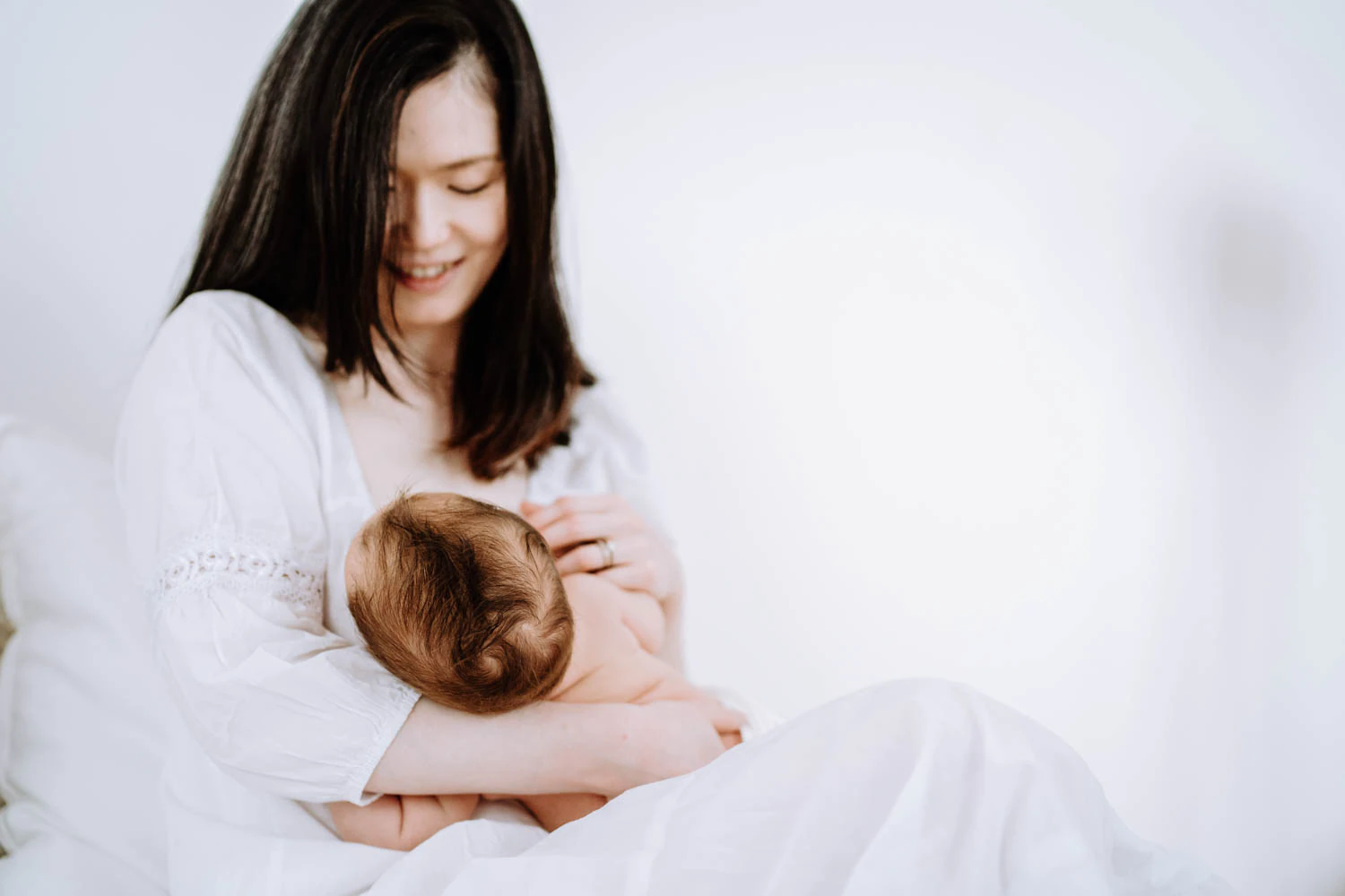 Mama hält ihr Baby im Arm - Cleane, helle Babyfotos im Fotostudio in Weilheim