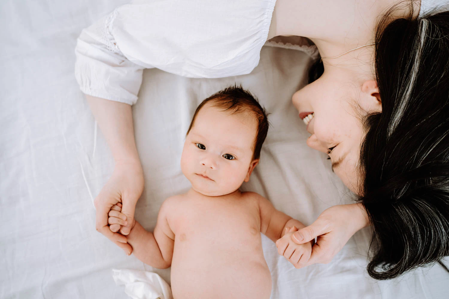 Mama kuschelt Baby, helle Bildwelt, zeitlose Studioaufnahme