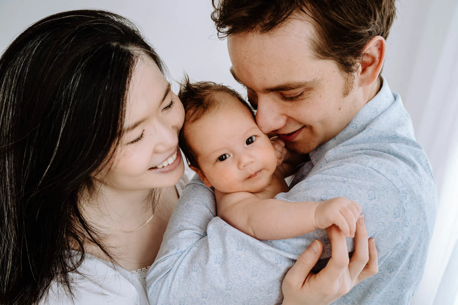 Eltern halten Baby im Arm, weißer Hintergrund, cleanes Familienfoto