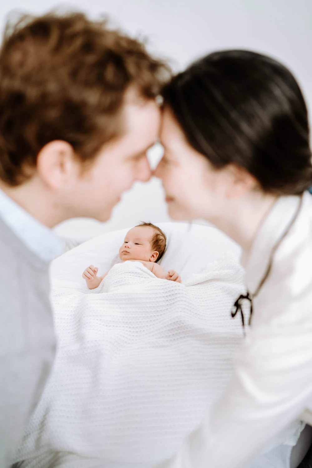 Baby in Seitenlage, weiße Textilien, zeitlose Newbornaufnahme