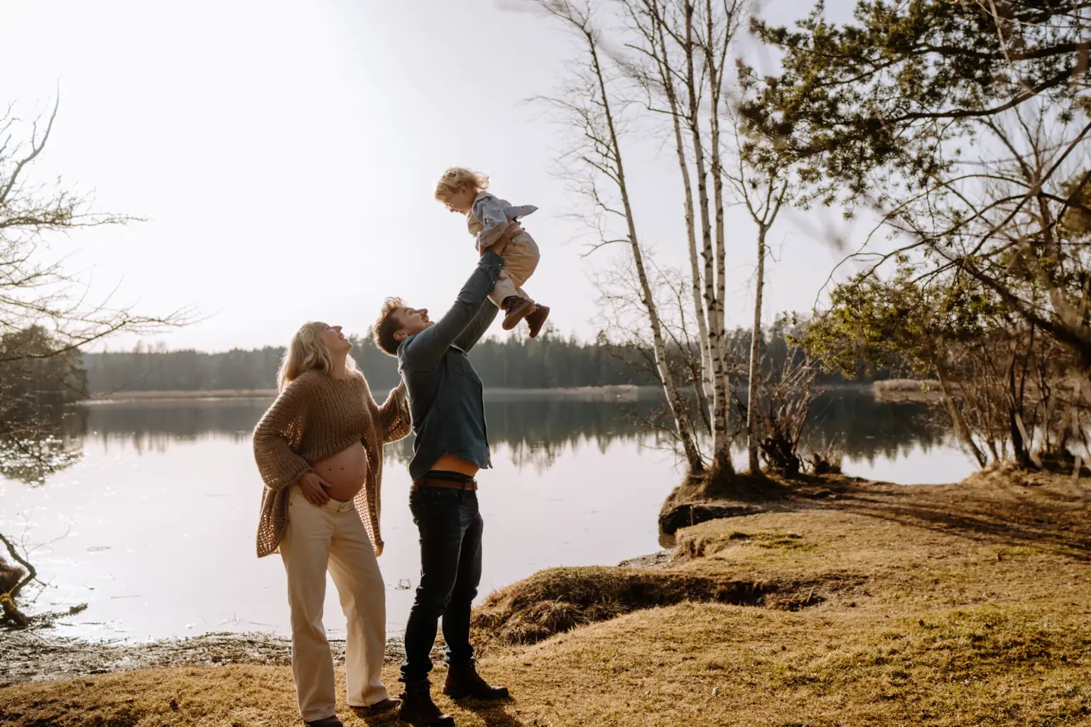 Familienfoto mit Babybauch in Weilheim, Eltern und Kind lachen draußen